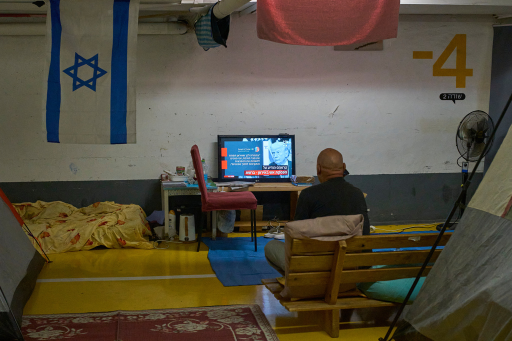 A man sits inside a shelter watching television news after a two-week ceasefire with Iran was announced, in Tel Aviv, Israel, Wednesday, April 8, 2026. (AP Photo/Ohad Zwigenberg)