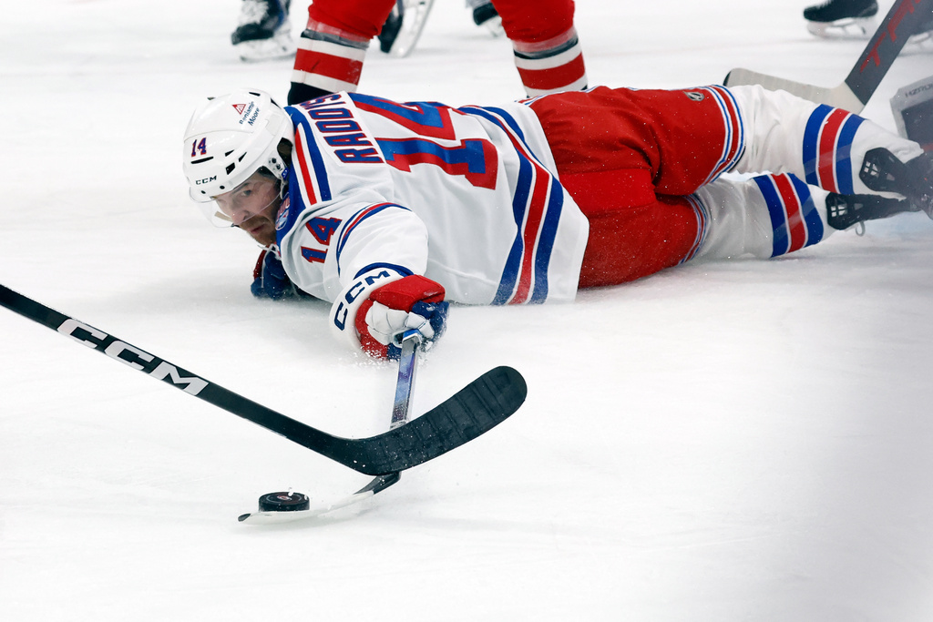 New York Rangers' Taylor Raddysh (14) stretches for the puck against the Carolina Hurricanes during the first period of an NHL hockey game, in Raleigh, N.C., Monday, Dec. 29, 2025. (AP Photo/Karl DeBlaker)