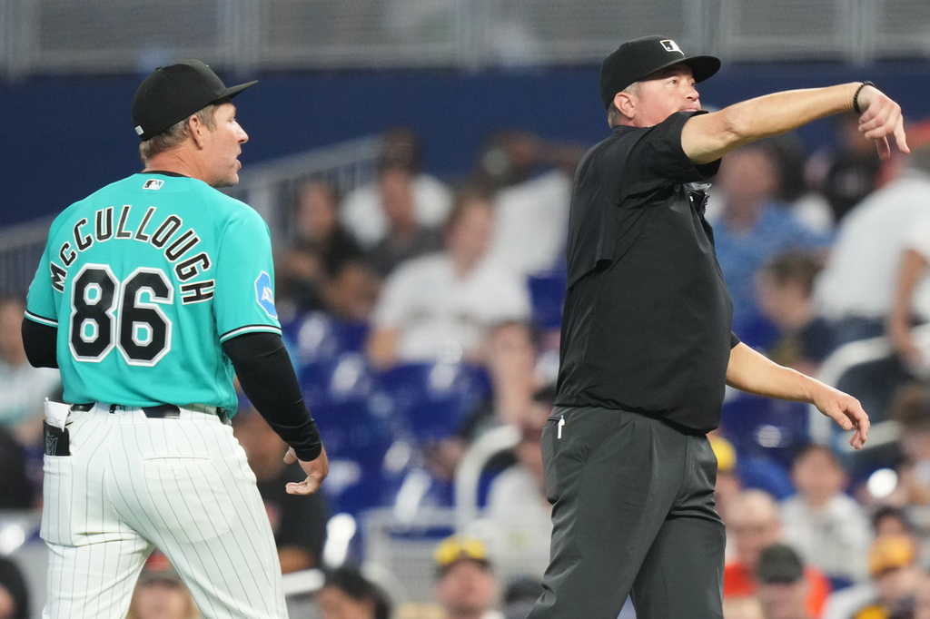 Miami Marlins manager Clayton McCullough (86) is ejected by first base umpire Cory Blaser, right, during the first inning of a baseball game against the Milwaukee Brewers, Sunday, April 19, 2026, in Miami. (AP Photo/Lynne Sladky)