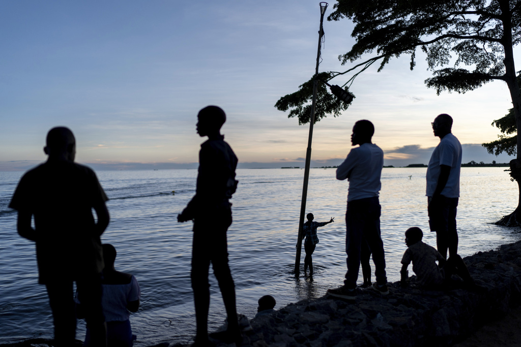 A youth group wades into the waters of Lake Victoria, the world's second-largest freshwater lake, while visiting a beach at sunset, Monday, Nov. 25, 2024, in Entebbe, Uganda. (AP Photo/David Goldman)