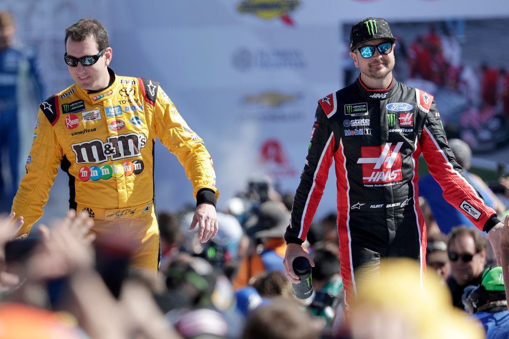 FILE - Kyle Busch, left, and Kurt Busch, right, greet fans as they are introduced before the NASCAR Daytona 500 auto race at Daytona International Speedway in Daytona Beach, Fla., Feb. 18, 2018. (AP Photo/John Raoux, File)