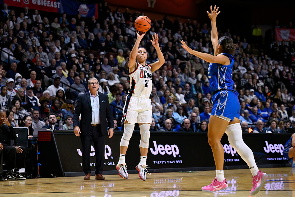 FILE - UConn guard Azzi Fudd (35) shoots over Creighton guard Jayme Horan (12) as UConn head coach Geno Auriemma looks on during the second half of an NCAA college basketball game in the finals of the Big East Conference tournament, Monday, March 10, 2025, in Uncasville, Conn. (AP Photo/Jessica Hill, File)