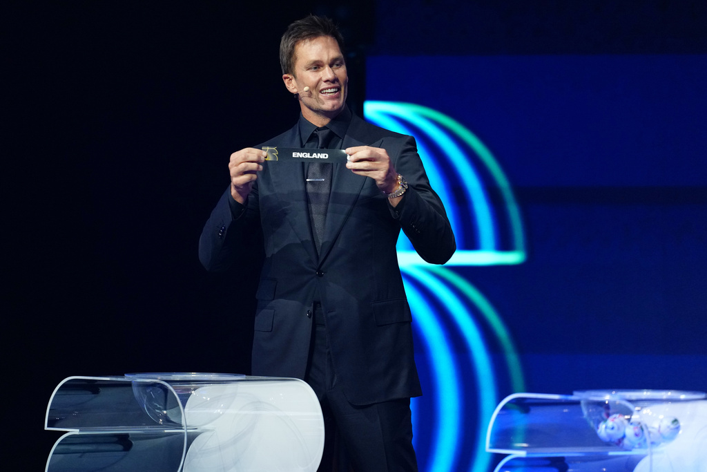 Former NFL player Tom Brady holds up the name of England during the draw for the 2026 soccer World Cup at the Kennedy Center in Washington, Friday, Dec. 5, 2025. (Jia Haocheng/Pool Photo via AP)