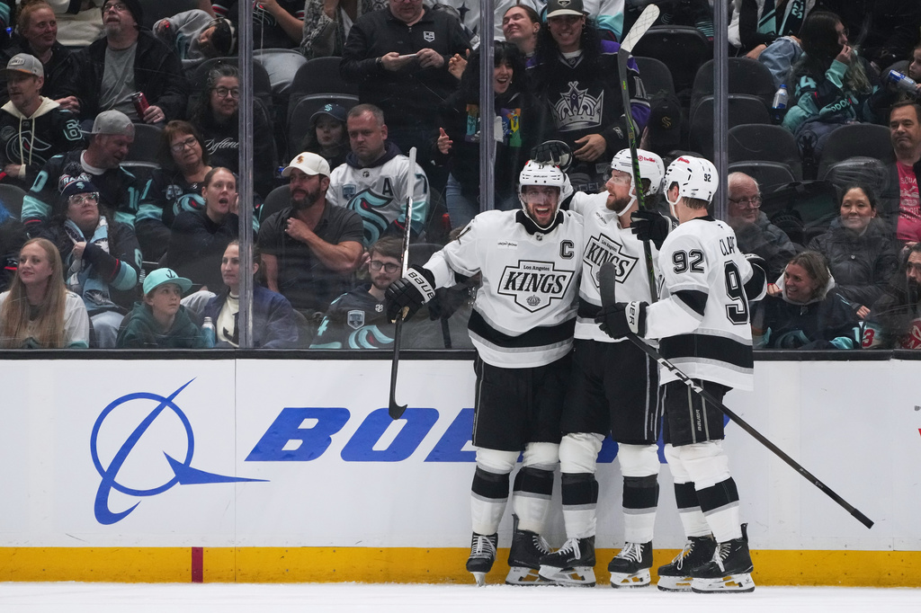 Los Angeles Kings right wing Adrian Kempe, center, celebrates his goal with center Anze Kopitar, left, and defenseman Brandt Clarke, right, against the Seattle Kraken during the third period of an NHL hockey game Monday, April 13, 2026, in Seattle. (AP Photo/Lindsey Wasson)