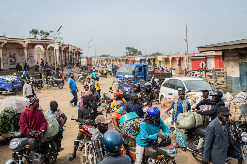 Motorcycle taxi riders and their passengers wait at the entrance to the central market while sanitation workers disinfect the area, as Ituri province continues to combat an Ebola outbreak in Bunia, Congo, Saturday, May 23, 2026. (AP Photo/Moses Sawasawa)