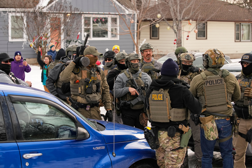Federal immigration officers prepare to make an arrest Sunday, Jan. 11, 2026, in Minneapolis. (AP Photo/John Locher)
