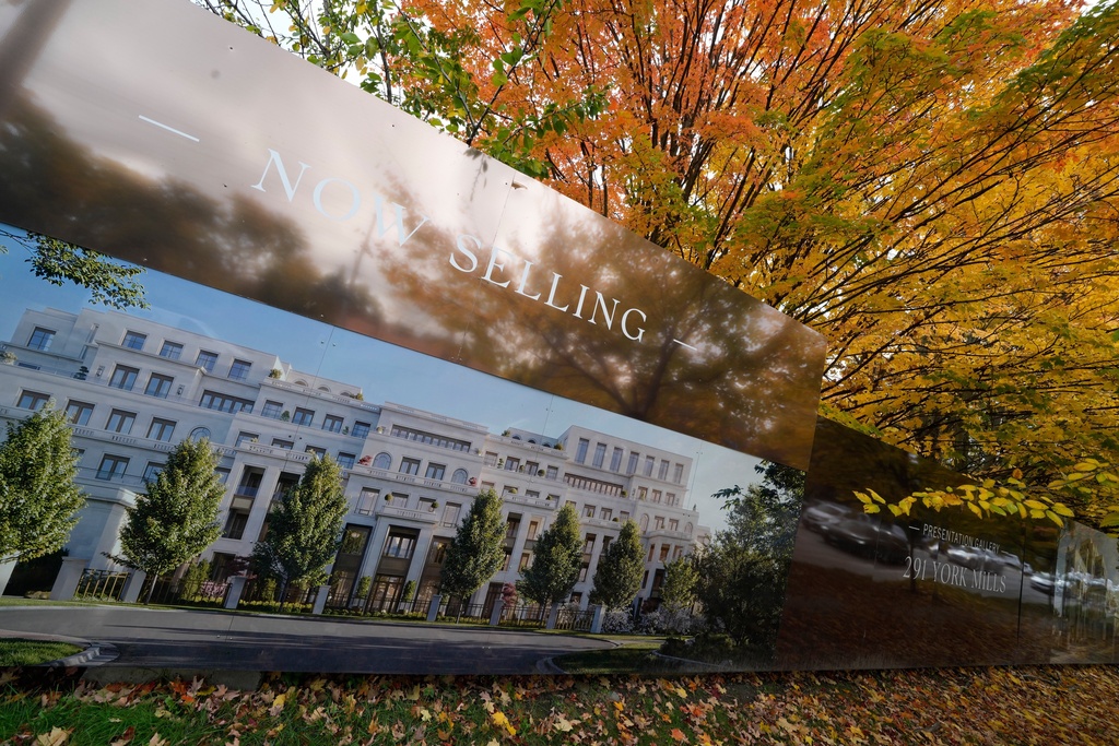 Vehicles are reflected on a residential project advertising billboard under the colorful trees in Toronto, Wednesday, Oct. 22, 2025. (AP Photo/Kamran Jebreili)