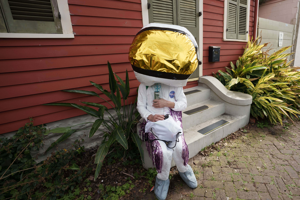 A person participating in the Society of Saint Anne parade sits on a front stoop of a buidling during Mardi Gras Day, Tuesday, Feb. 17, 2026 in New Orleans. (AP Photo/Matthew Hinton)