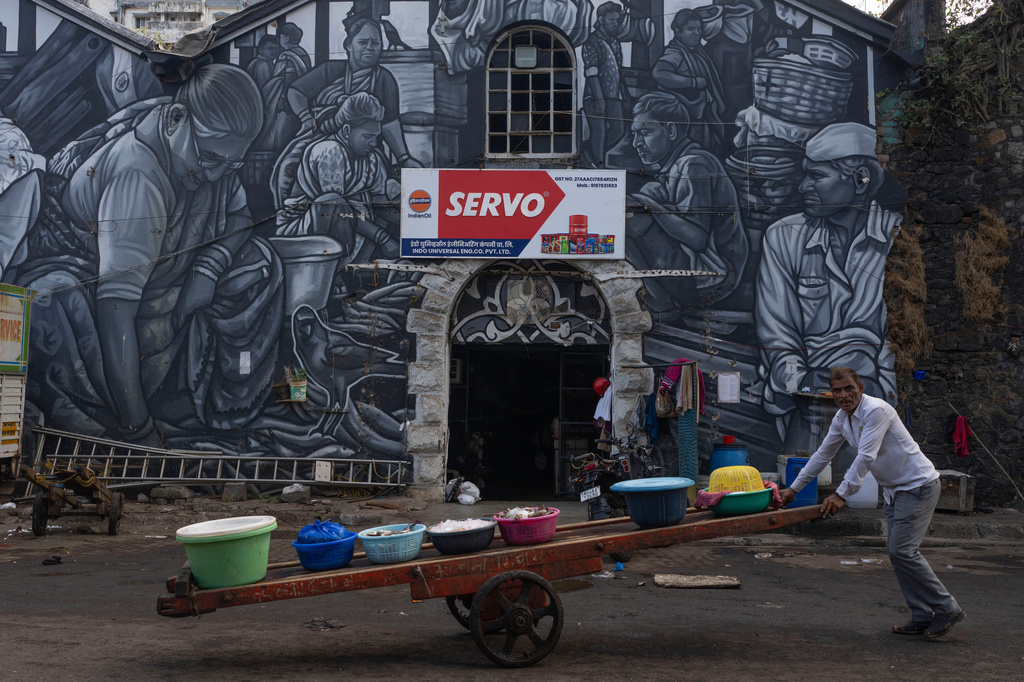 A fisherman pushes his cart filled with catch as he passes by a mural of the fisher community at Sassoon Dock In Mumbai, India, Wednesday, April 8, 2026. (AP Photo/Rafiq Maqbool)