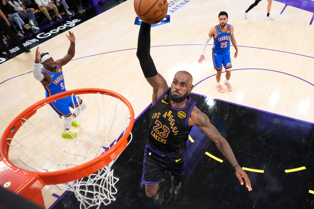 Los Angeles Lakers forward LeBron James, center, goes up for a dunk as Oklahoma City Thunder guard Luguentz Dort, left, and guard Ajay Mitchell watch during the second half of Game 4 in a second-round NBA basketball playoffs series Monday, May 11, 2026, in Los Angeles. (AP Photo/Mark J. Terrill)