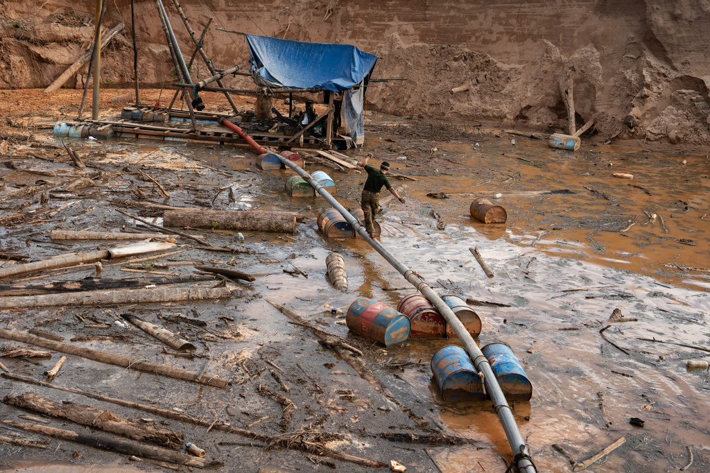 A Peruvian Navy soldier walks over a pipe to get to a dredge used for illegal mining near the Malinowski River in the Tambopata National Reserve in Puerto Maldonado, Peru, Tuesday, Aug. 11, 2026. (AP Photo/Guadalupe Pardo)