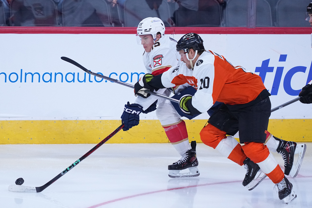 Florida Panthers center Anton Lundell, left, and Philadelphia Flyers right wing Bobby Brink, right, vie for the puck during the first period of an NHL hockey game, Monday, Oct. 13, 2025, in Philadelphia. (AP Photo/Matt Rourke)