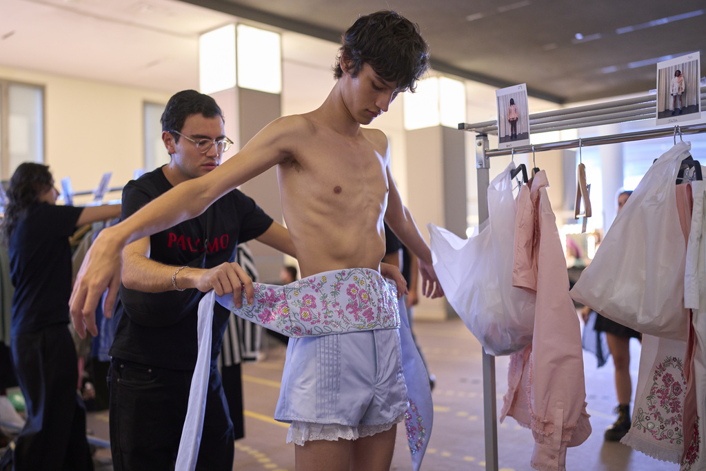 A model is being dressed by an assistant backstage at the brand's show during Fashion Week in Madrid, Spain, Wednesday, Sept. 17, 2025. (AP Photo/Manu Fernandez)