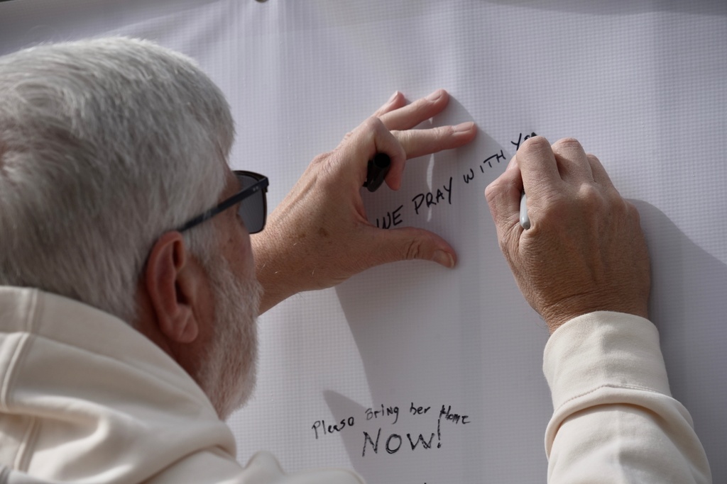 Jeff Robb, a Seattle resident wintering in Tucson, signs a banner supporting Nancy Guthrie in Tucson Ariz., on Friday, Feb. 13, 2026. (AP Photo/Ty ONeil)