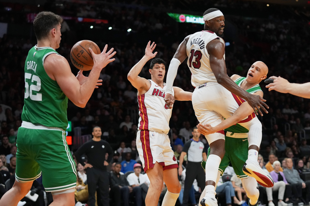 Boston Celtics guard Jordan Walsh, right, passes the ball to center Luka Garza (52) past Miami Heat center Bam Adebayo (13) during the first half of an NBA basketball game, Wednesday, April 1, 2026, in Miami. (AP Photo/Lynne Sladky)
