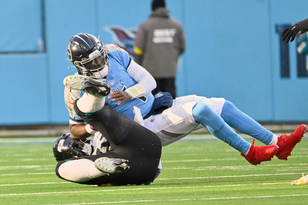 Jacksonville Jaguars defensive end Josh Hines-Allen, left, sacks Tennessee Titans quarterback Cam Ward during the second half of an NFL football game Sunday, Nov. 30, 2025, in Nashville, Tenn. (AP Photo/John Amis)