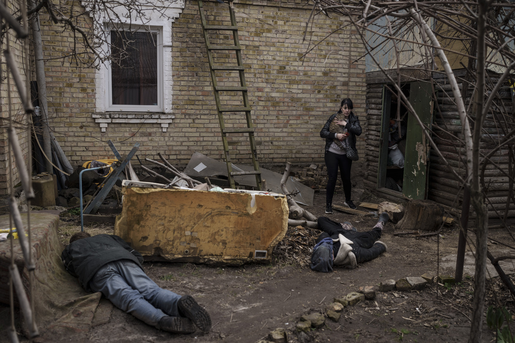 FILE - Ira Gavriluk holds her cat as she walks next to the bodies of her husband, brother, and another man, who were killed outside her home in Bucha, on the outskirts of Kyiv, Ukraine, April 4, 2022. (AP Photo/Felipe Dana, File)
