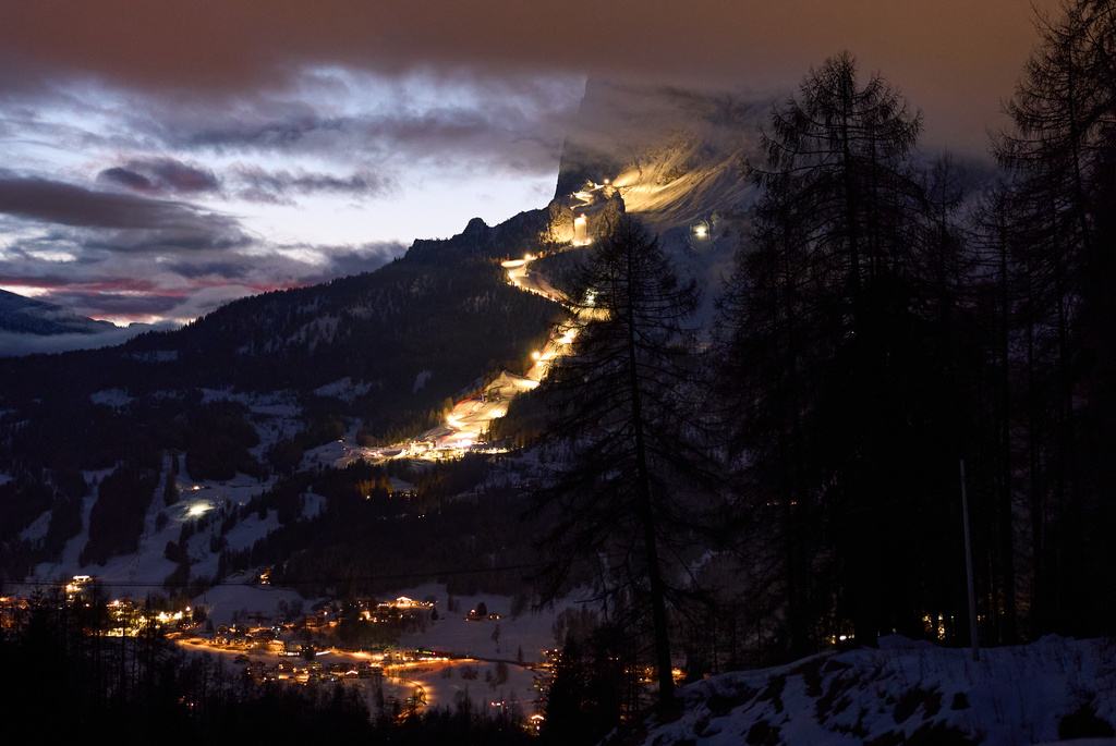 The course for the women's Olympic alpine ski competitions is seen lit up at dusk, with Cortina d'Ampezzo, in the foreground, during the 2026 Winter Olympics, in Cortina d'Ampezzo, Italy, Wednesday, Feb. 11, 2026. (AP Photo/Jacquelyn Martin)