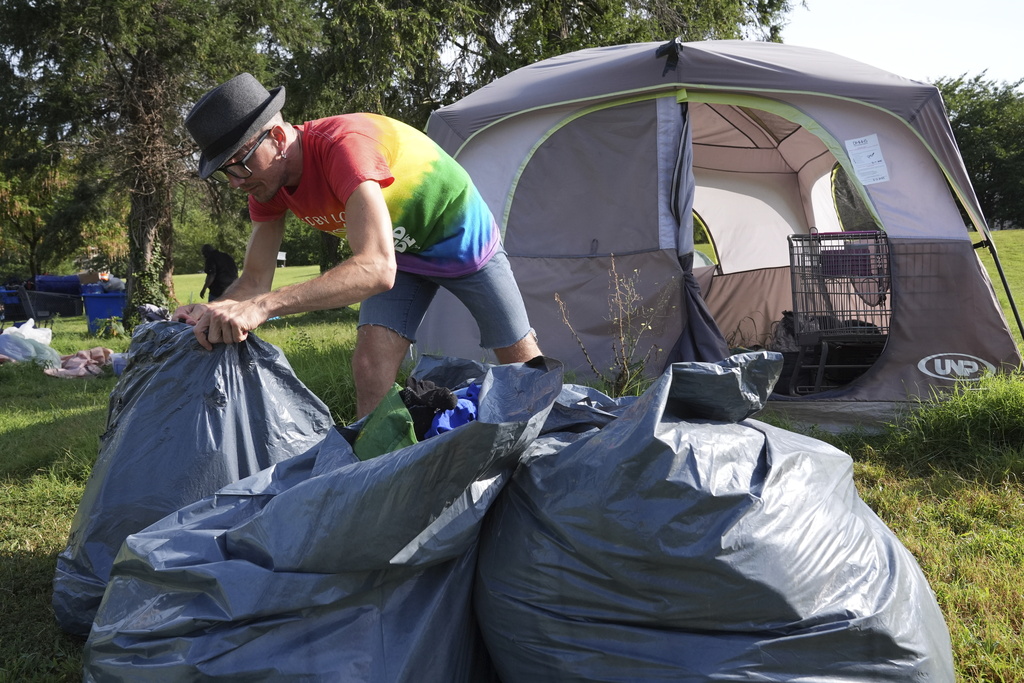 Jesse Wall, 43, clears up a tent encampment, Thursday, Aug. 14, 2025, where people who are homeless have been living in Washington. (AP Photo/Jacquelyn Martin)