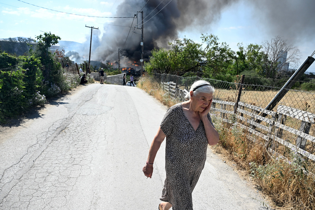 A woman reacts during a wildfire on the outskirts of the northern city of Thessaloniki, Greece, Sunday, July 5, 2026. (AP Photo/Giannis Papanikos)