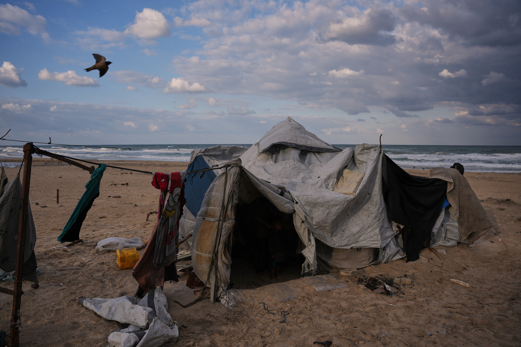 A bird flies over a damaged tent following recent days of rain in a makeshift camp for displaced Palestinians set up on the beach in Gaza City, Tuesday, Dec. 16, 2025. (AP Photo/Abdel Kareem Hana)