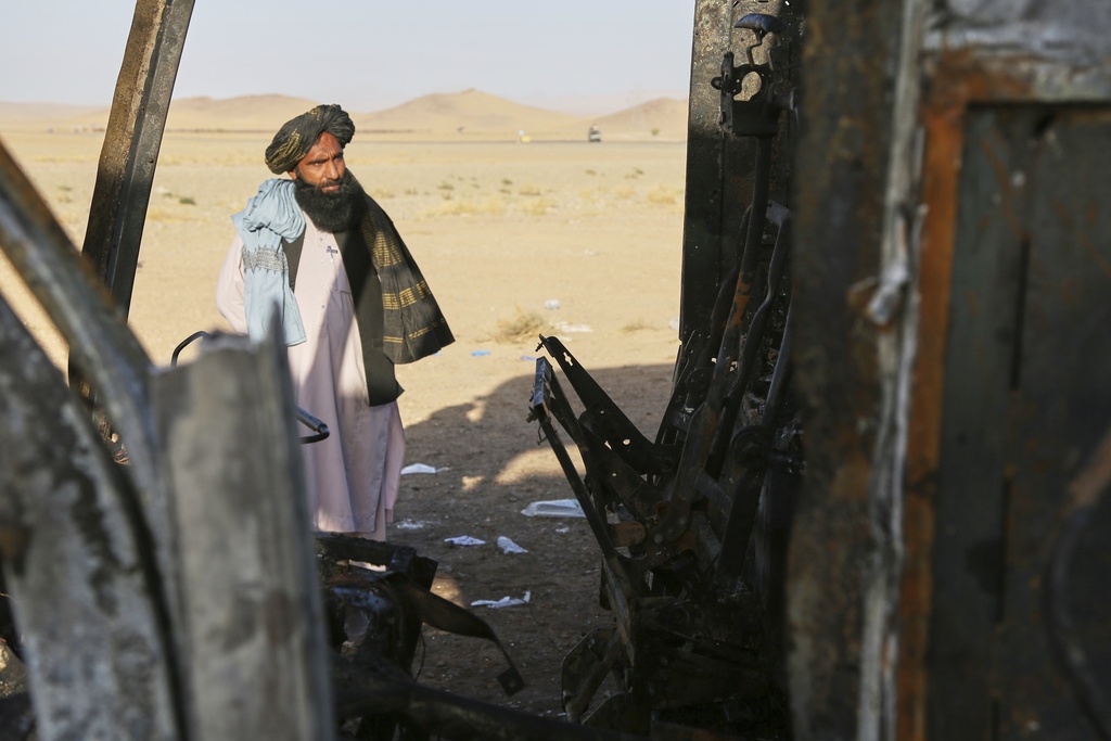 A man looks at a burned-out bus that collided with a truck and a motorbike Tuesday evening, causing a massive fire and killing at least 70 people, including children, most of them Afghans returning from Iran, in western Herat province, Afghanistan, Wednesday, Aug. 20, 2025. (AP Photo/Omid Haqjoo)