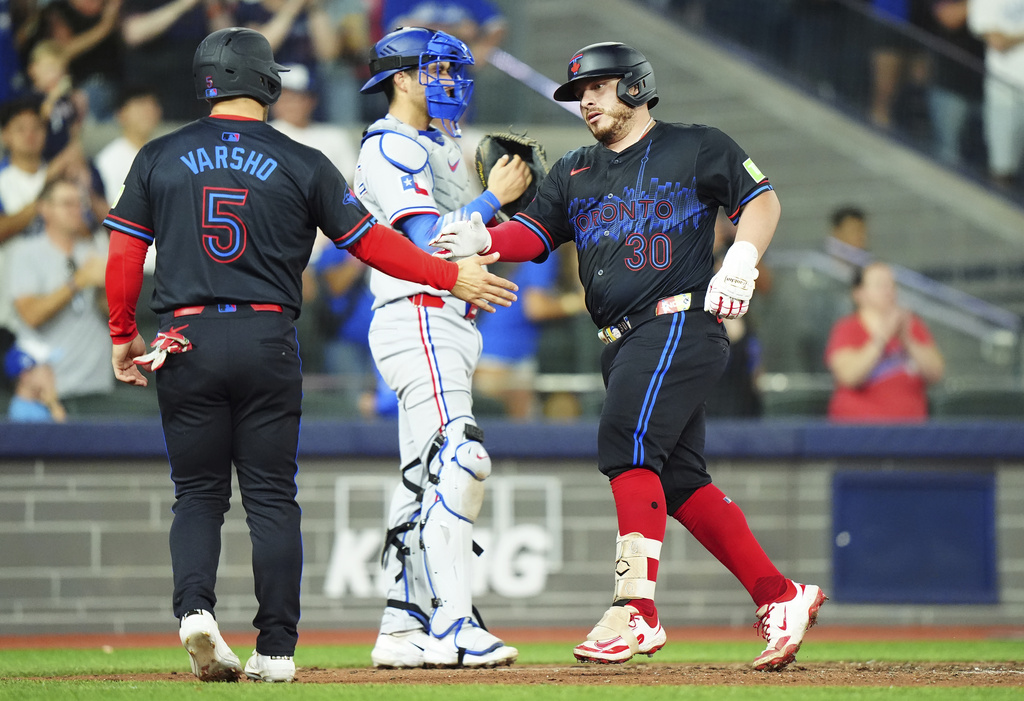 Toronto Blue Jays' Alejandro Kirk, right, celebrates his two-run home run against the Texas Rangers with teammate Daulton Varsho during the seventh inning of a baseball game in Toronto on Friday, Aug. 15, 2025. (Frank Gunn/The Canadian Press via AP)