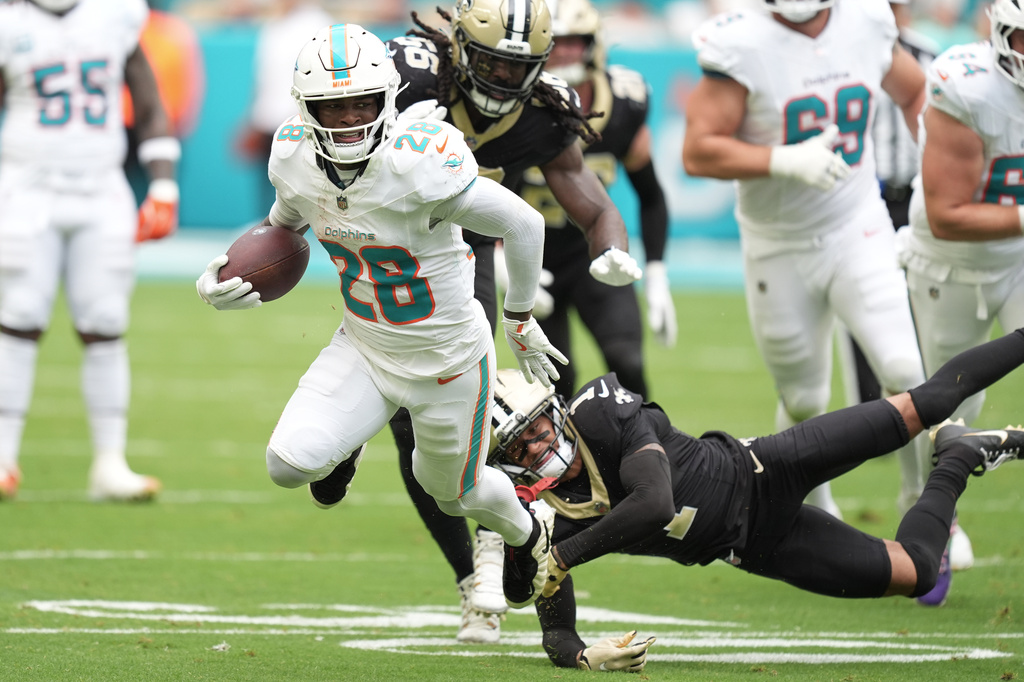 FILE - Miami Dolphins running back De'Von Achane (28) escapes a tackle by New Orleans Saints cornerback Alontae Taylor (1) during the first half of an NFL football game, Nov. 30, 2025, in Miami Gardens, Fla. (AP Photo/Rebecca Blackwell, File)
