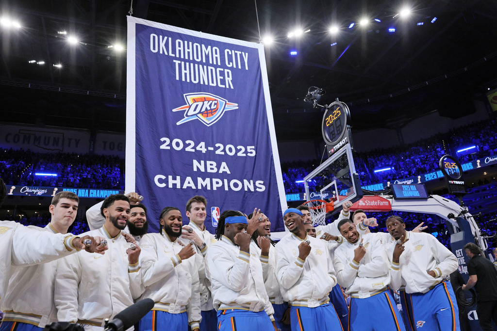 The Oklahoma City Thunder pose with their championship rings in front of the 2024-2025 NBA Champions banner during a ceremony before an NBA basketball game against the Houston Rockets, Tuesday, Oct. 21, 2025, in Oklahoma City. (AP Photo/Nate Billings)