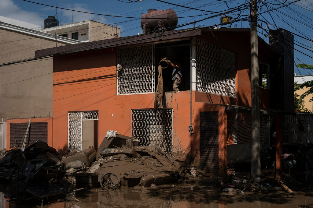 A local cleans a flooded house in Poza Rica, Veracruz state, Mexico, Sunday, Oct. 12, 2025. (AP Photo/Felix Marquez)