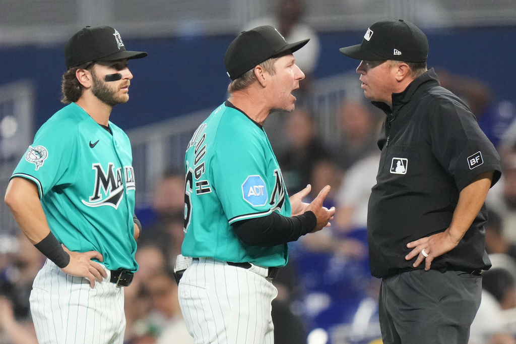 Miami Marlins manager Clayton McCullough, center, argues a call with first base umpire Cory Blaser, right, as first baseman Connor Norby, left, looks on during the first inning of a baseball game against the Milwaukee Brewers, Sunday, April 19, 2026, in Miami. (AP Photo/Lynne Sladky)