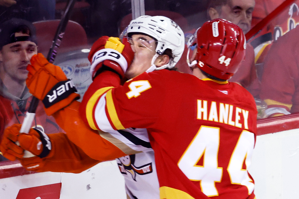 Anaheim Ducks' Olen Zellweger, left, takes a hard hit from Calgary Flames' Joel Hanley during the second period of an NHL hockey game in Calgary, Thursday, March 26, 2026. (Larry MacDougal/The Canadian Press via AP)