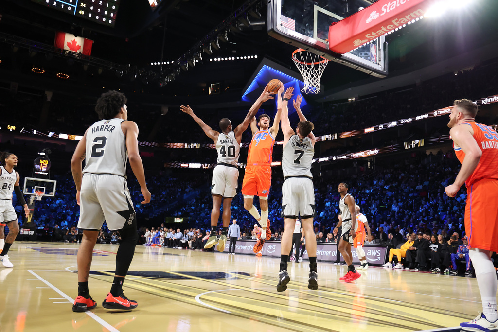 Oklahoma City Thunder center Chet Holmgren (7) jumps up for a shot near San Antonio Spurs' Harrison Barnes (40) and Luke Kornet (7) in the first half of an NBA Cup semifinals basketball game, Saturday, Dec. 13, 2025, in Las Vegas. (AP Photo/Ronda Churchill)