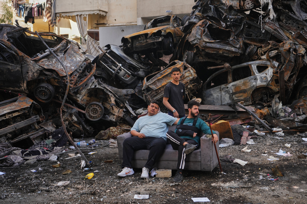 Residents sit on a sofa in front of charred cars at the site of a building destroyed in an Israeli airstrike last Wednesday in central Beirut, Lebanon, Tuesday, April 14, 2026. (AP Photo/Hassan Ammar)