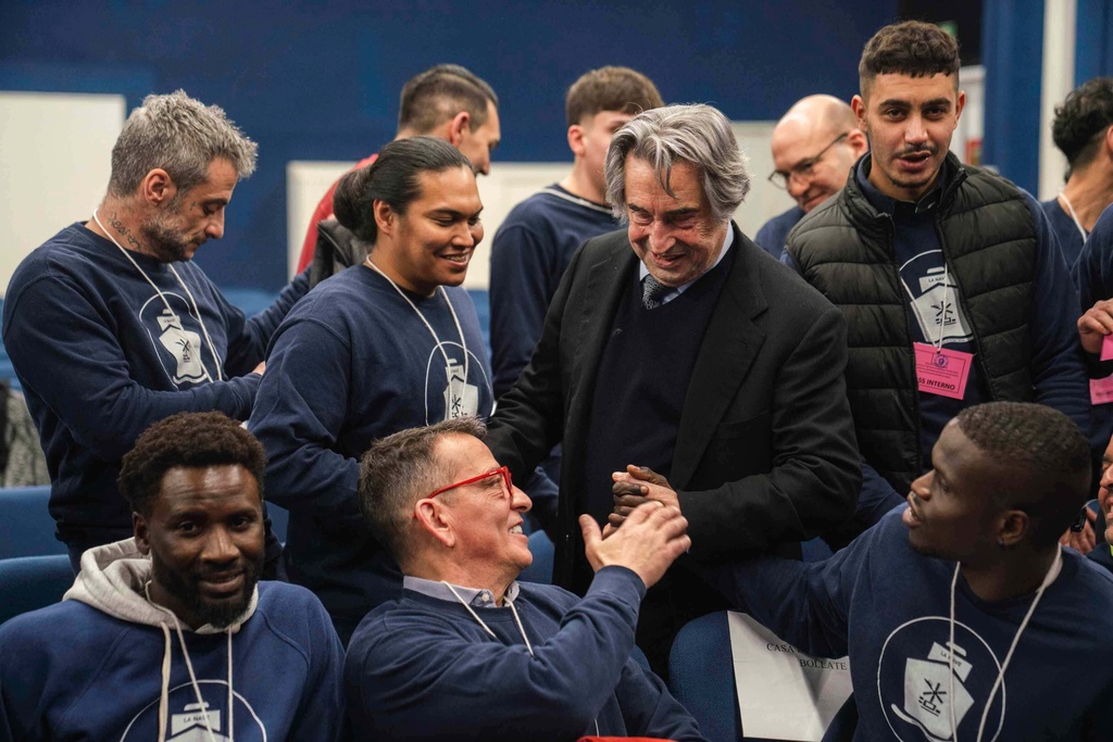 This image, distributed on Monday, Jan. 12, 2026, by Fondazione Casa Dello Spirito e delle Arti, shows conductor Riccardo Muti being cheered by inmates at Opera Prison in Milan, northern Italy, on Saturday, Jan. 10, 2026, after performing inside the prison with the Orchestra del Mare using musical instruments made from the timber of sunken migrant ships. (Marco Borrelli/Fondazione Casa Dello Spirito e delle Arti via AP, HO)