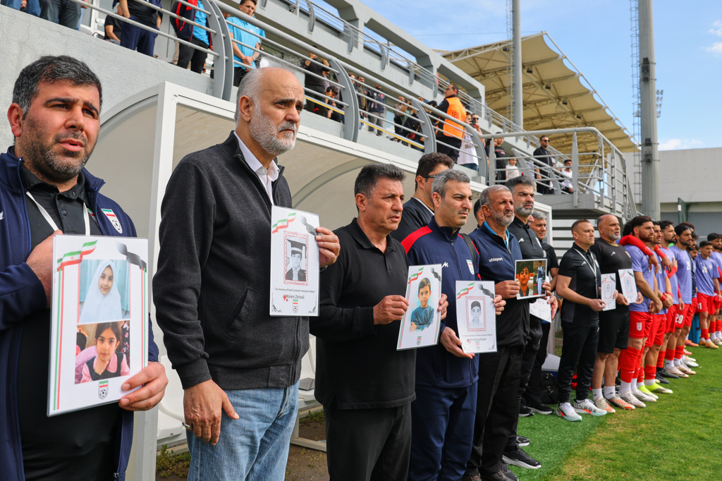 Iran's Football Federation Vice President Mehdi Mohammad Nabi, second left, Iran's coach Amir Ghalenoei, third left, and team members hold pictures of children allegedly killed in U.S. and Israel strikes in Iran, before a friendly soccer match between Iran and Costa Rica, in Antalya, southern Turkey, Tuesday, March 31, 2026. (AP Photo/Riza Ozel)
