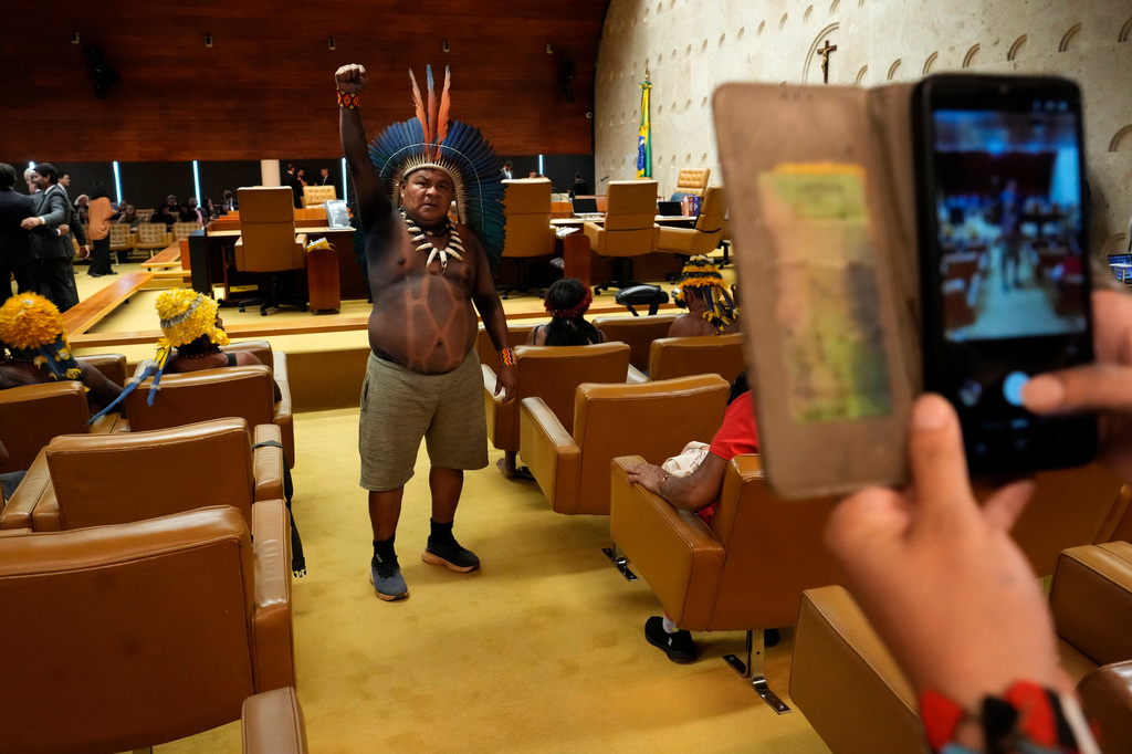 Tupinamba Indigenous leader Gilson Tupinamba raises a fist while posing for a photo inside Brazil's Supreme Court courtroom before a session, where justices will discuss a case about reducing the size of Jamanxim National Park, in Brasilia, Wednesday, April 8, 2026. (AP Photo/Eraldo Peres)