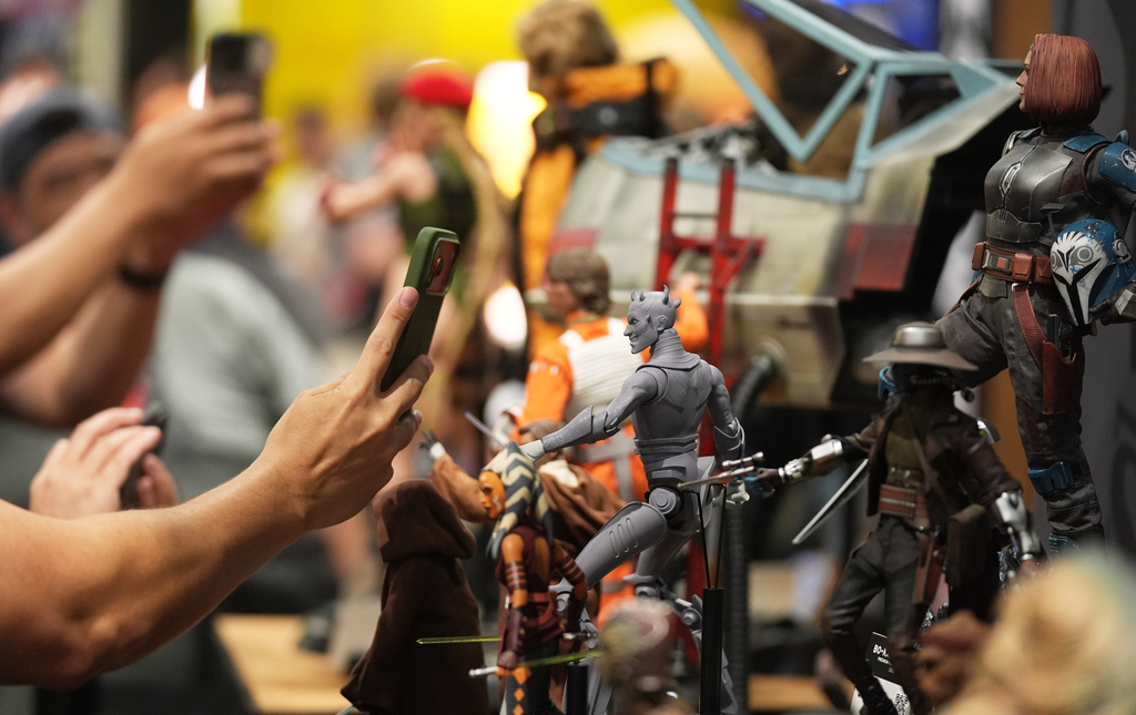 Comic-Con attendees take pictures of model figures at the Sideshow Collectibles booth during preview night at Comic-Con International on Wednesday, July 22, 2026, in San Diego. (AP Photo/Chris Pizzello)