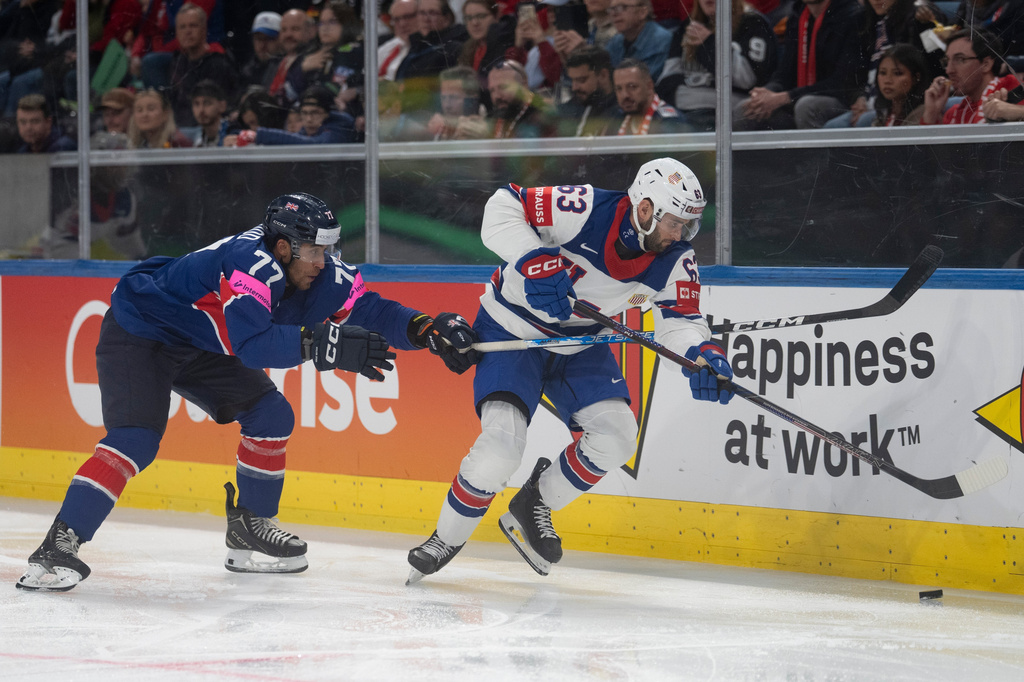 USA's Max Sasson, right, fights for the puck with Britain's Bayley Harewood, during the 2026 IIHF Men's Ice Hockey World Championship preliminary round group A game between Britain and the United States, in Zurich, Switzerland, Sunday, May 17, 2026. (Claudio Thoma/Keystone via AP)