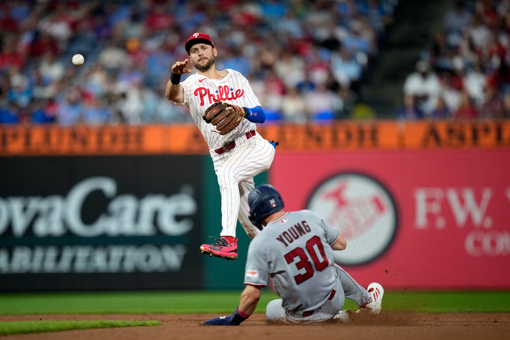 Philadelphia Phillies shortstop Trea Turner, left, throws to first after forcing out Washington Nationals' Jacob Young at second on a double play hit into by CJ Abrams during the fifth inning of a baseball game Wednesday, Aug. 5, 2026, in Philadelphia. (AP Photo/Matt Slocum)