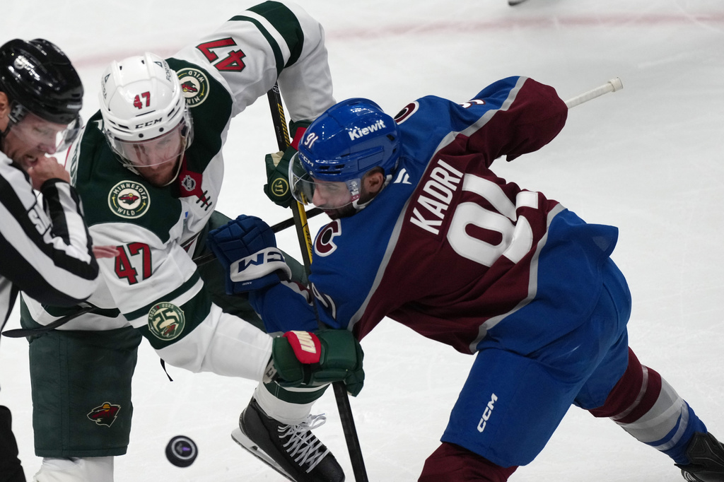 Minnesota Wild center Michael McCarron, left, fights for control of the puck with Colorado Avalanche center Nazem Kadri in the first period of Game 1 of an NHL hockey Stanley Cup second-round playoff series, Sunday, May 3, 2026, in Denver. (AP Photo/David Zalubowski)