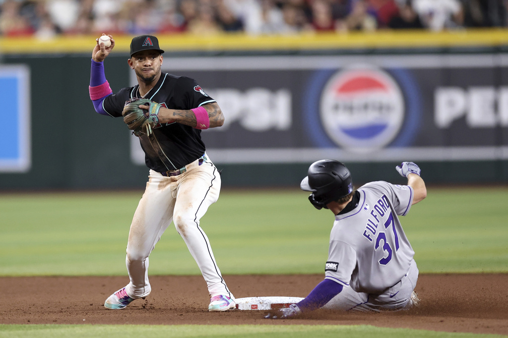 Arizona Diamondbacks second baseman Ketel Marte, left, turns a double play over Colorado Rockies' Braxton Fulford (37) during the eighth inning of a baseball game Saturday, Aug. 9, 2025, in Phoenix. (AP Photo/Chris Coduto)
