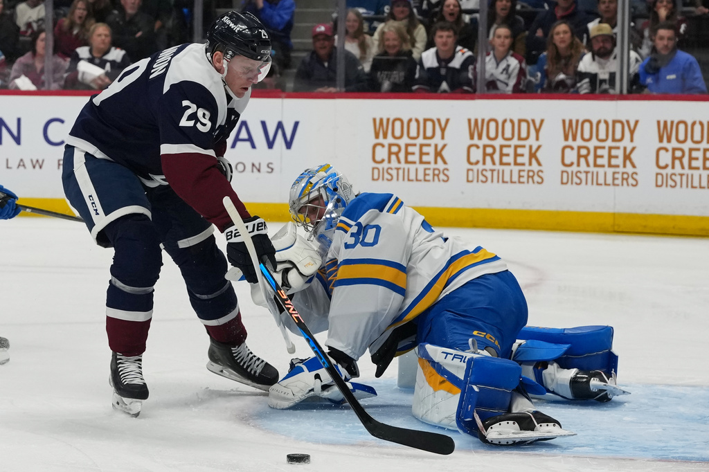 St. Louis Blues goaltender Joel Hofer, right, stops a shot by Colorado Avalanche center Nathan MacKinnon in the first period of an NHL hockey game Sunday, April 5, 2026, in Denver. (AP Photo/David Zalubowski)