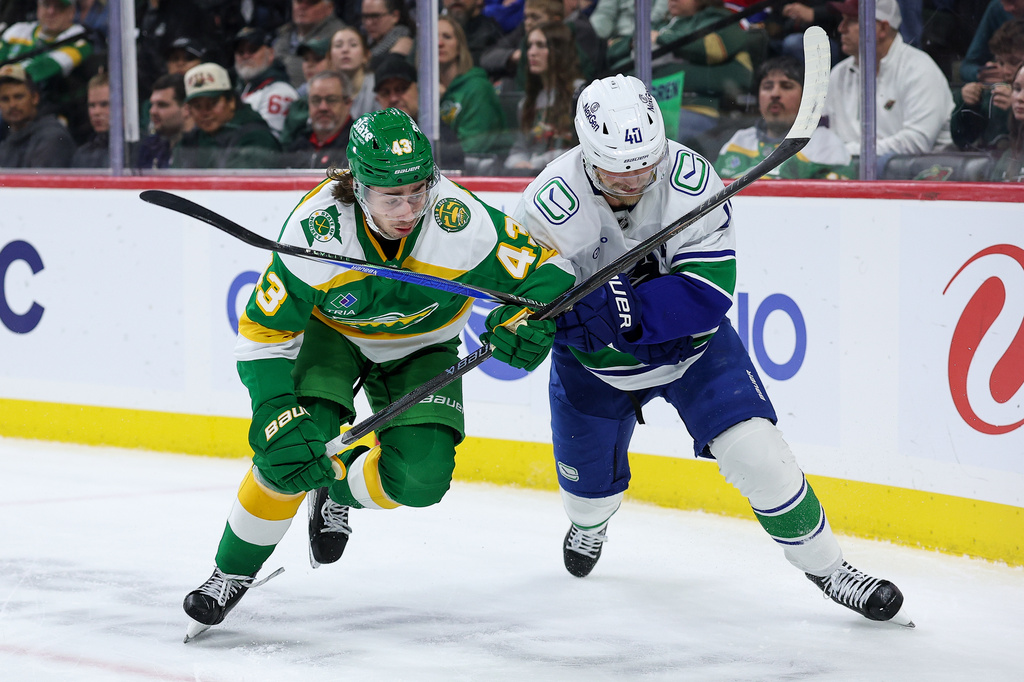 Minnesota Wild defenseman Quinn Hughes, left, and Vancouver Canucks center Elias Pettersson (40) compete for the puck during the second period of an NHL hockey game Thursday, April 2, 2026, in St. Paul, Minn. (AP Photo/Matt Krohn)