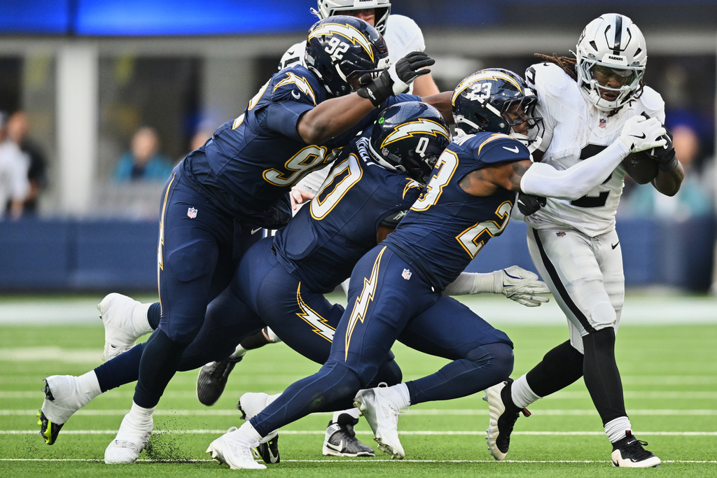 Las Vegas Raiders running back Ashton Jeanty, right, is tackled by Los Angeles Chargers defensive tackle Justin Eboigbe (92), linebacker Daiyan Henley (0) and safety Tony Jefferson (23) during the first half of an NFL football game, Sunday, Nov. 30, 2025, in Inglewood, Calif. (AP Photo/William Liang)