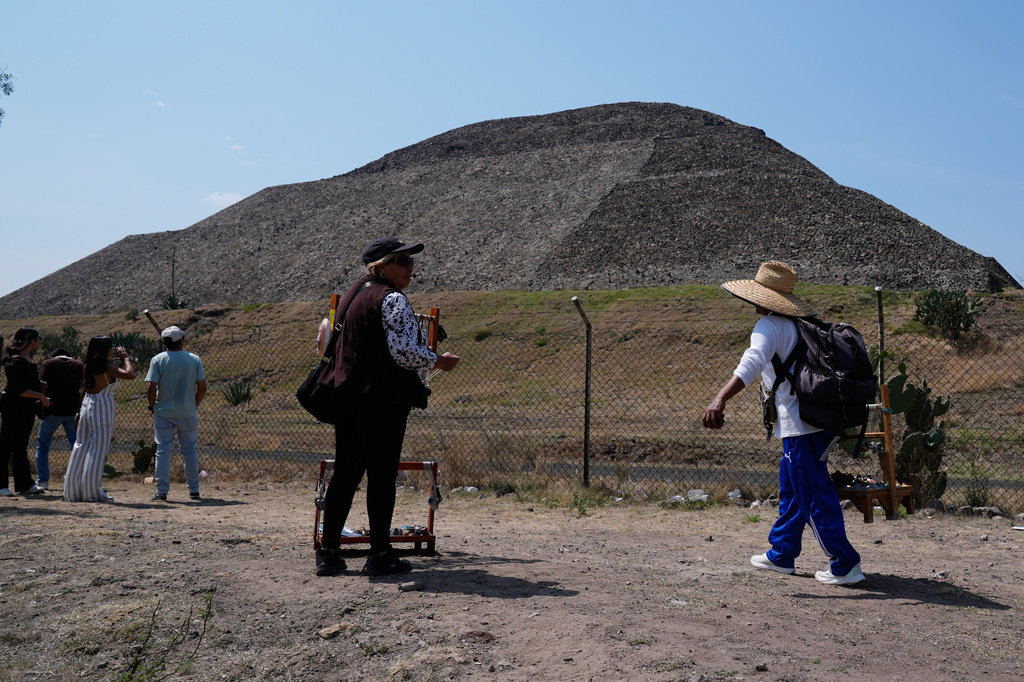 Handicraft vendors and tourists stand outside the Teotihuacan pyramids, which remained closed a day after a gunman opened fire on tourists at the archaeological site on the outskirts of Mexico City, Tuesday, April 21, 2026. (AP Photo/Marco Ugarte)