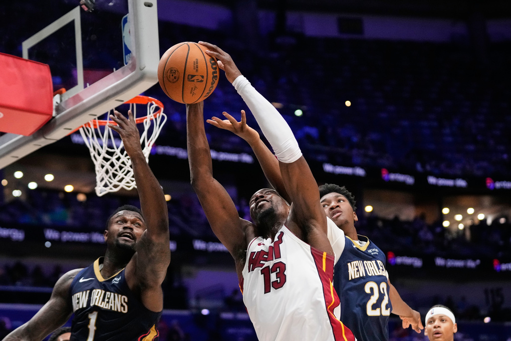 Miami Heat center Bam Adebayo (13) goes to the basket between New Orleans Pelicans forward Zion Williamson (1) and center Derik Queen (22) in the second half of an NBA basketball game, Wednesday, Feb. 11, 2026, in New Orleans. (AP Photo/Gerald Herbert)