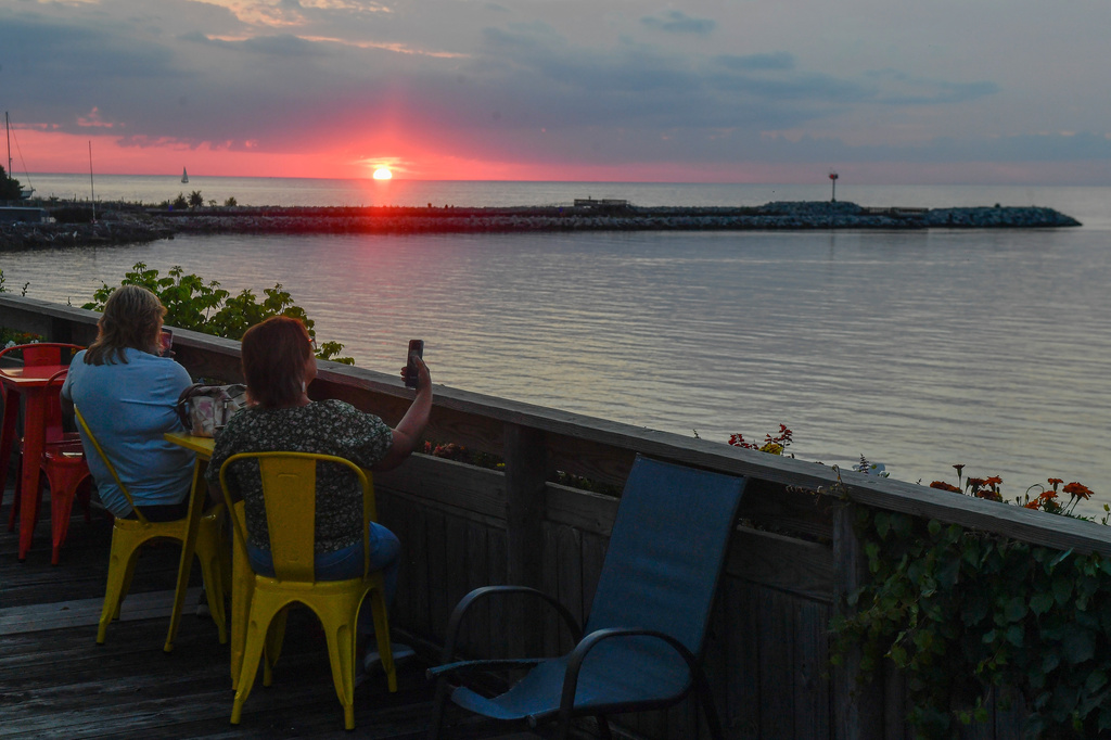 People watch the sun set over Lake Ontario, Tuesday, Aug. 25, 2026, in Olcott, N.Y. (AP Photo/Adrian Kraus)