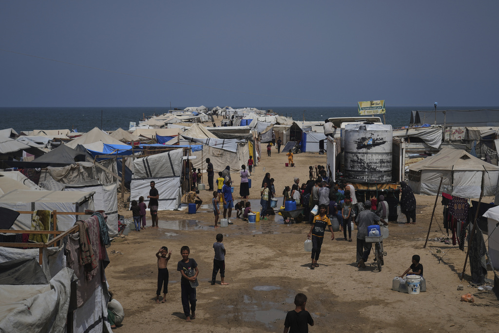 Displaced Palestinians gather to collect water from a truck during a heat wave at a makeshift tent camp in Khan Younis, Gaza Strip, Wednesday, Aug. 13, 2025. (AP Photo/Abdel Kareem Hana)