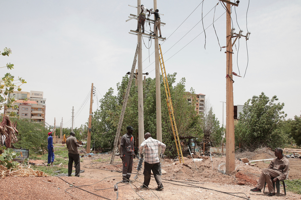 Workers fix electricity cables, previously destroyed during fighting between the Sudanese Armed Forces (SAF) and the paramilitary Rapid Support Forces (RSF), in Khartoum, Sudan, Monday, Aug. 18, 2025. (AP Photo/Marwan Ali)